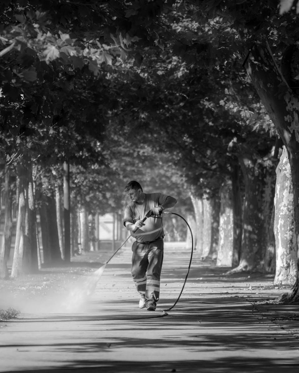 A man is walking down a street with a hose